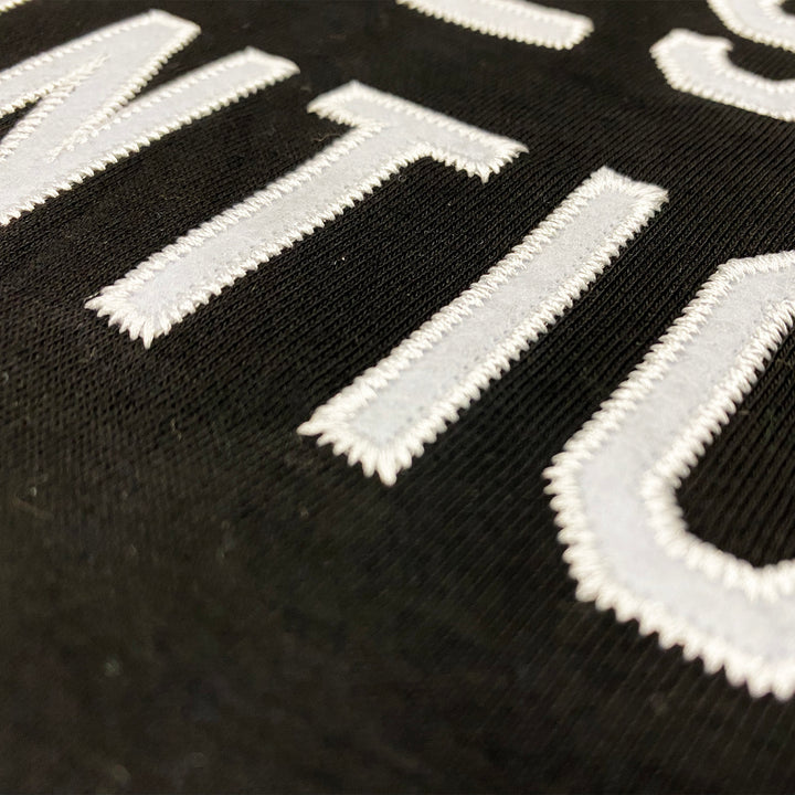  Close up image of a black crewneck sweatshirt with white felt letters that say hopeless romantic.